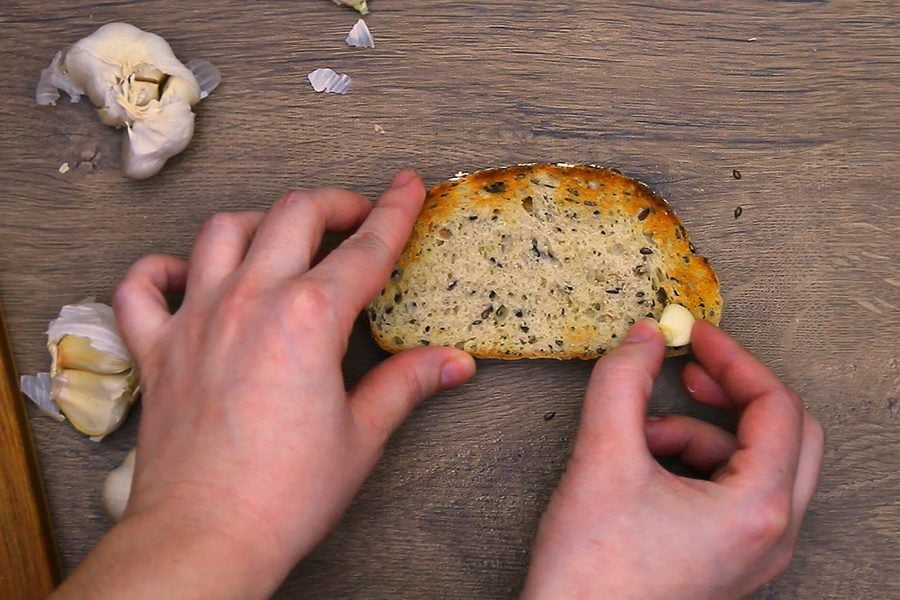 Rubbing a cut clove of garlic over a slice of toasted bread