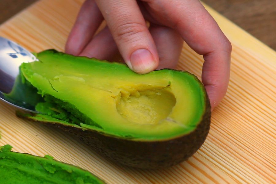 Scooping avocado out of the skin with a spoon