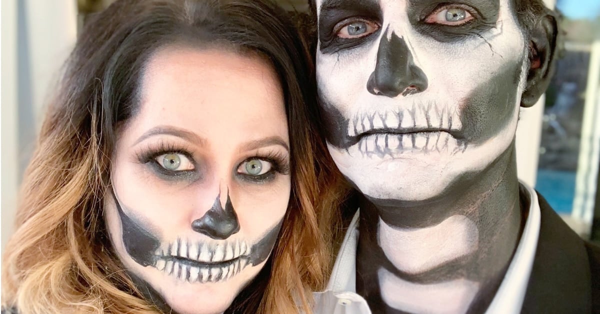 Skeleton couple Halloween makeup with black eye sockets, painted teeth, white face paint and matching black outfits