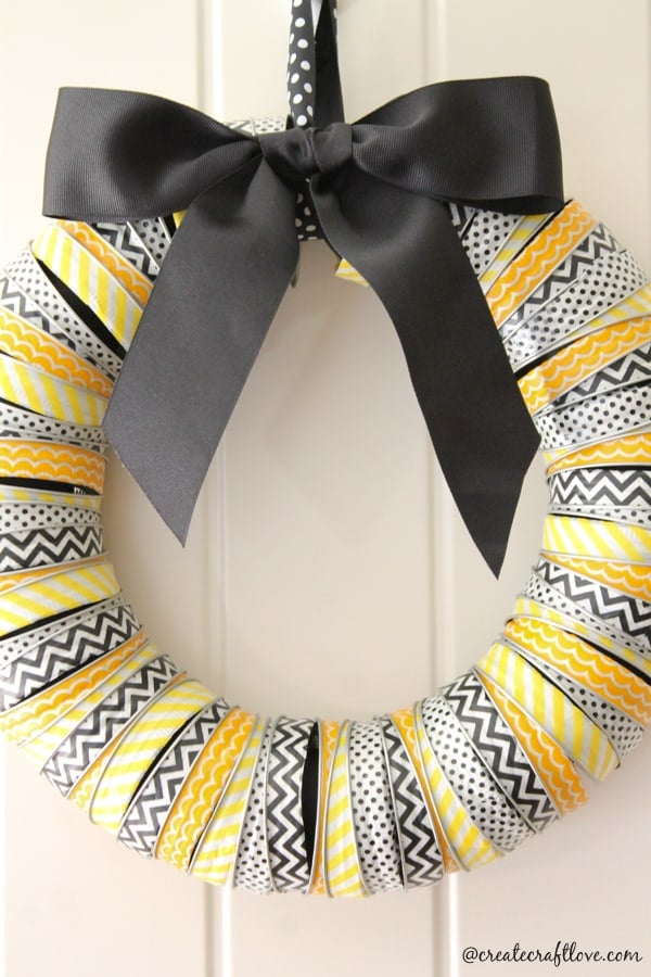 Black, white and yellow washi-tape-wrapped canning rings forming a Halloween wreath with a wide black ribbon bow
