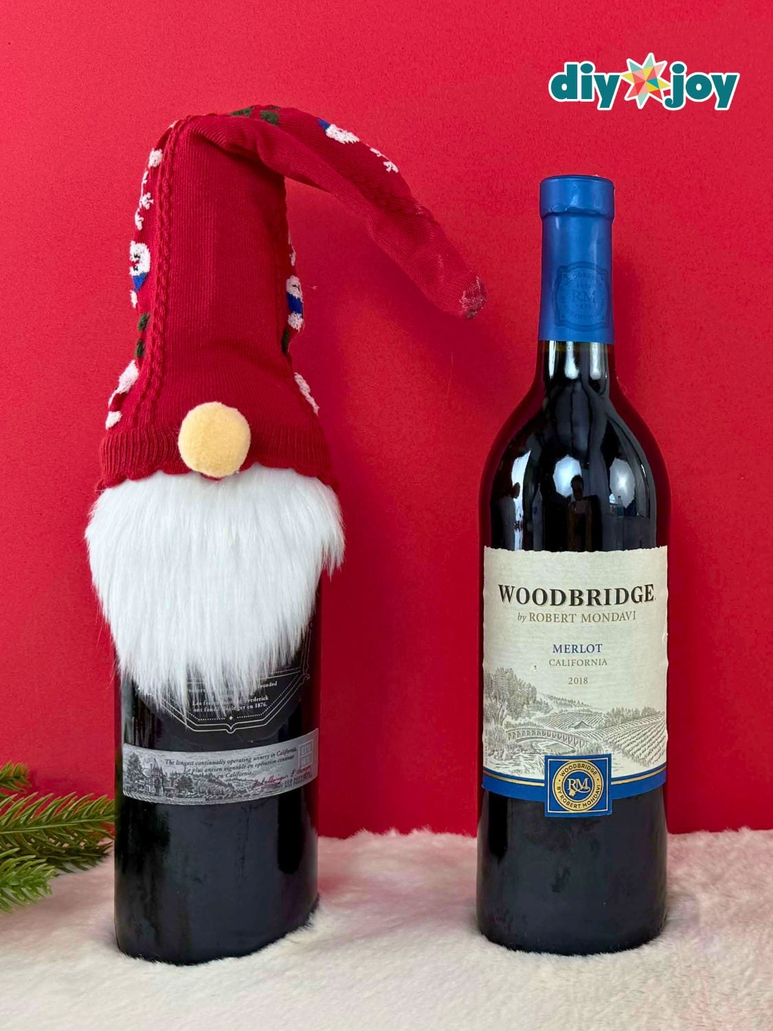 Wine bottle dressed as Santa in red felt with white trim, a black belt with gold buckle and a pointed hat
