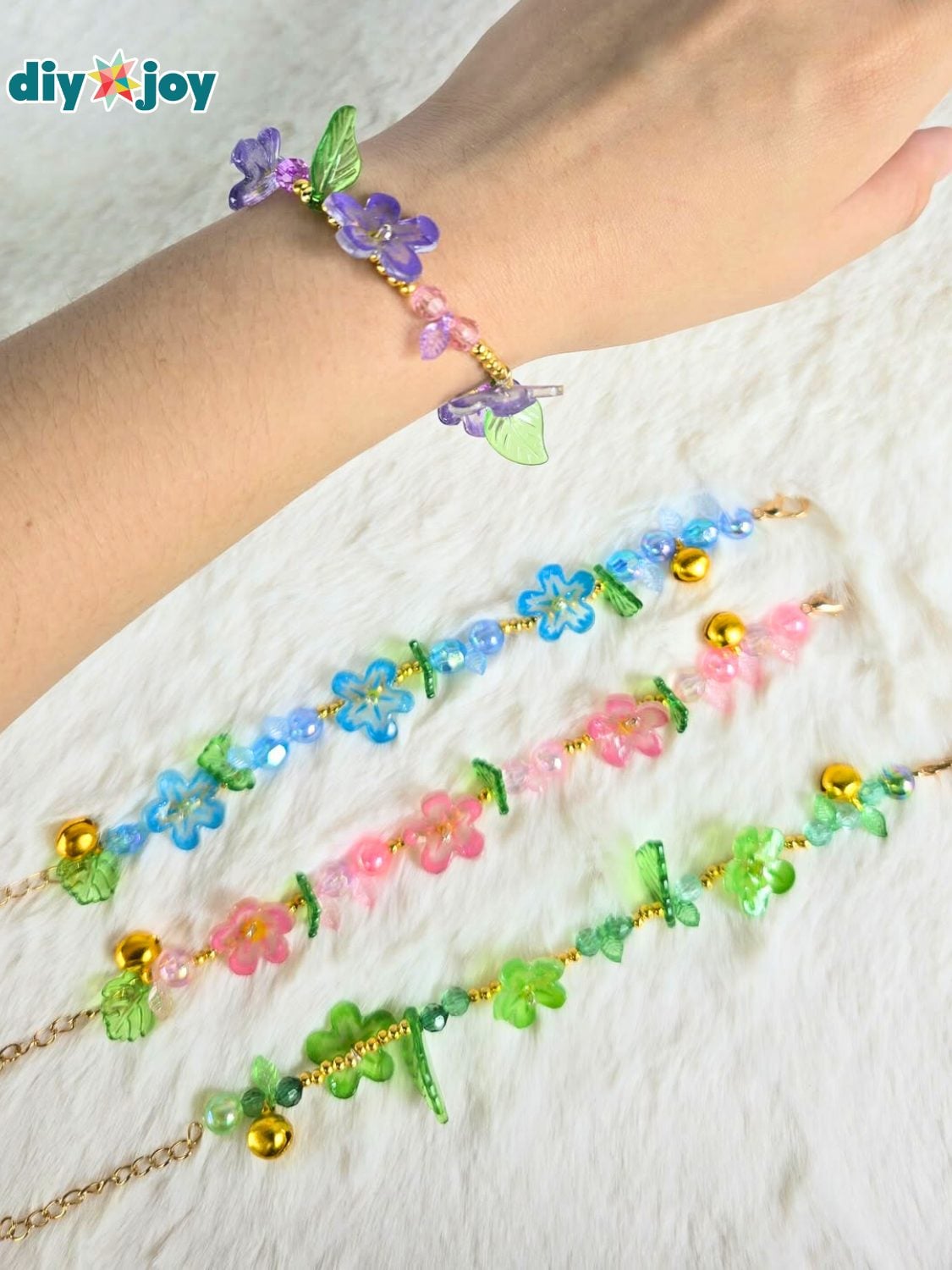 Stretch bracelet strung with glossy shrink plastic flower charms in pink, yellow and white on a pale surface