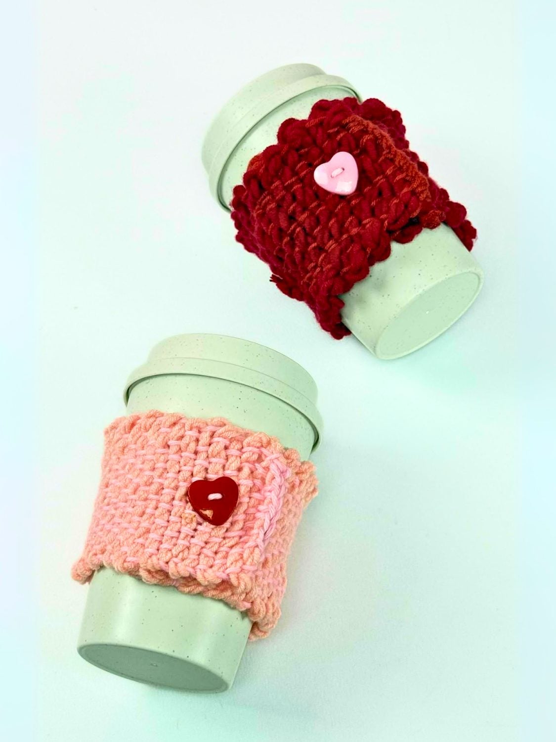 Plain white mug wrapped in a hand woven yarn cozy in cream and mustard stripes, sitting on a light table