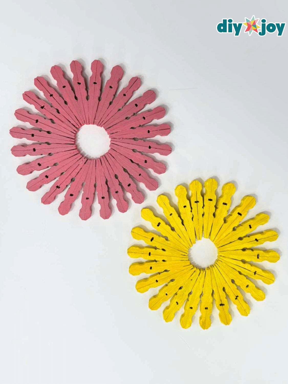 Pink and yellow sunburst trivets made from painted wooden clothespin halves glued in a ring on a white table