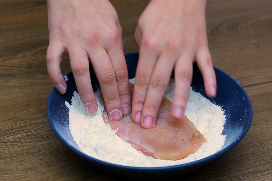 Easy Chicken Dinner Recipes, dredging a pounded chicken cutlet through seasoned flour before it goes into the hot pan