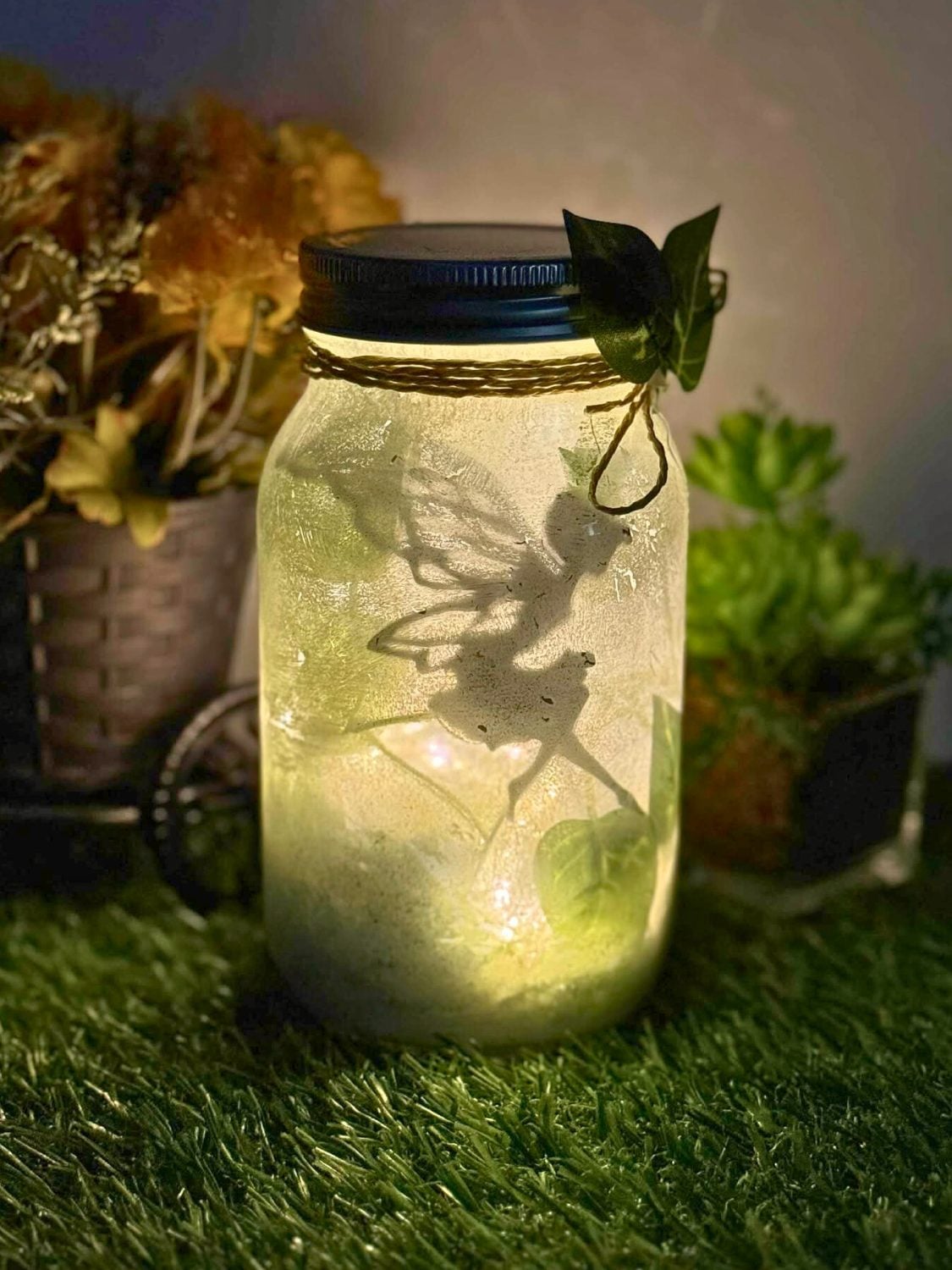 Glass jar filled with coiled warm white fairy lights glowing softly on a wooden table beside a dark window