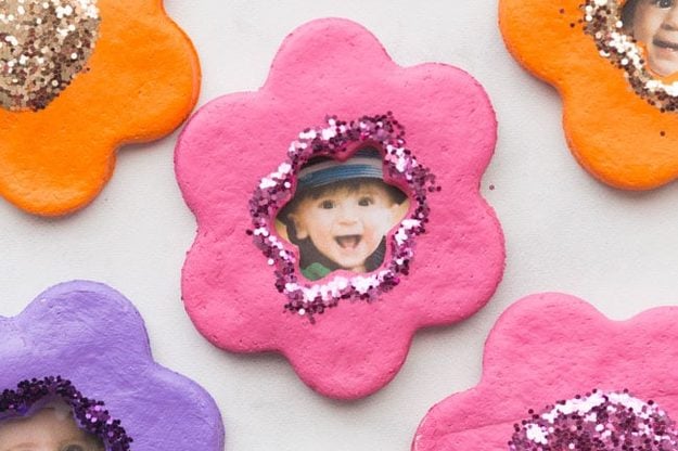 Salt dough flower shaped photo magnets glittered around a small photo center, a personalized craft to sell