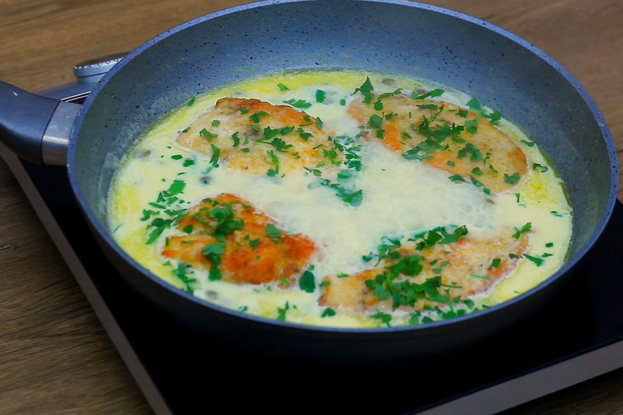 Creamy Chicken Piccata finished in the skillet, cutlets back in the lemon caper sauce with cream and fresh parsley