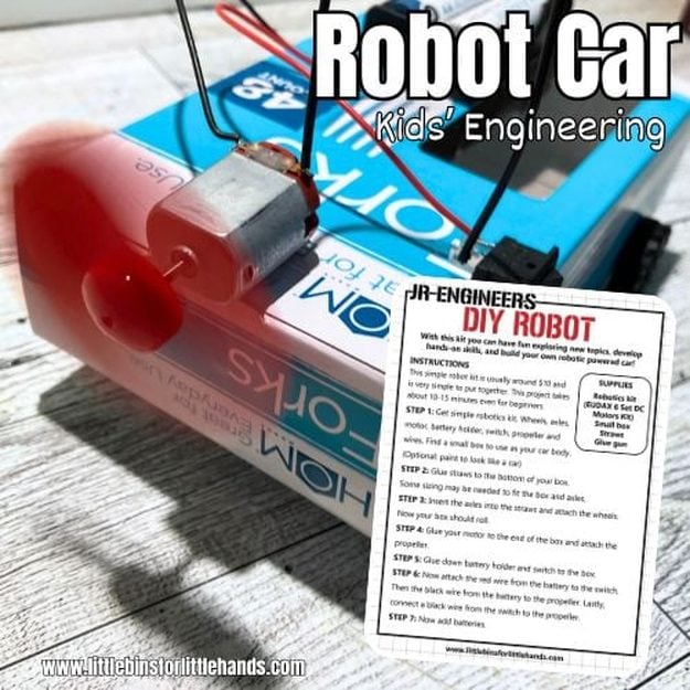 A small homemade robot car built from a cardboard box with straws for axles, a DC motor, propeller and wheels glued on top