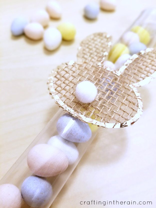 DIY burlap project, a burlap bunny shape cut with a Cricut and edged in rose gold foil on a tube of candy eggs