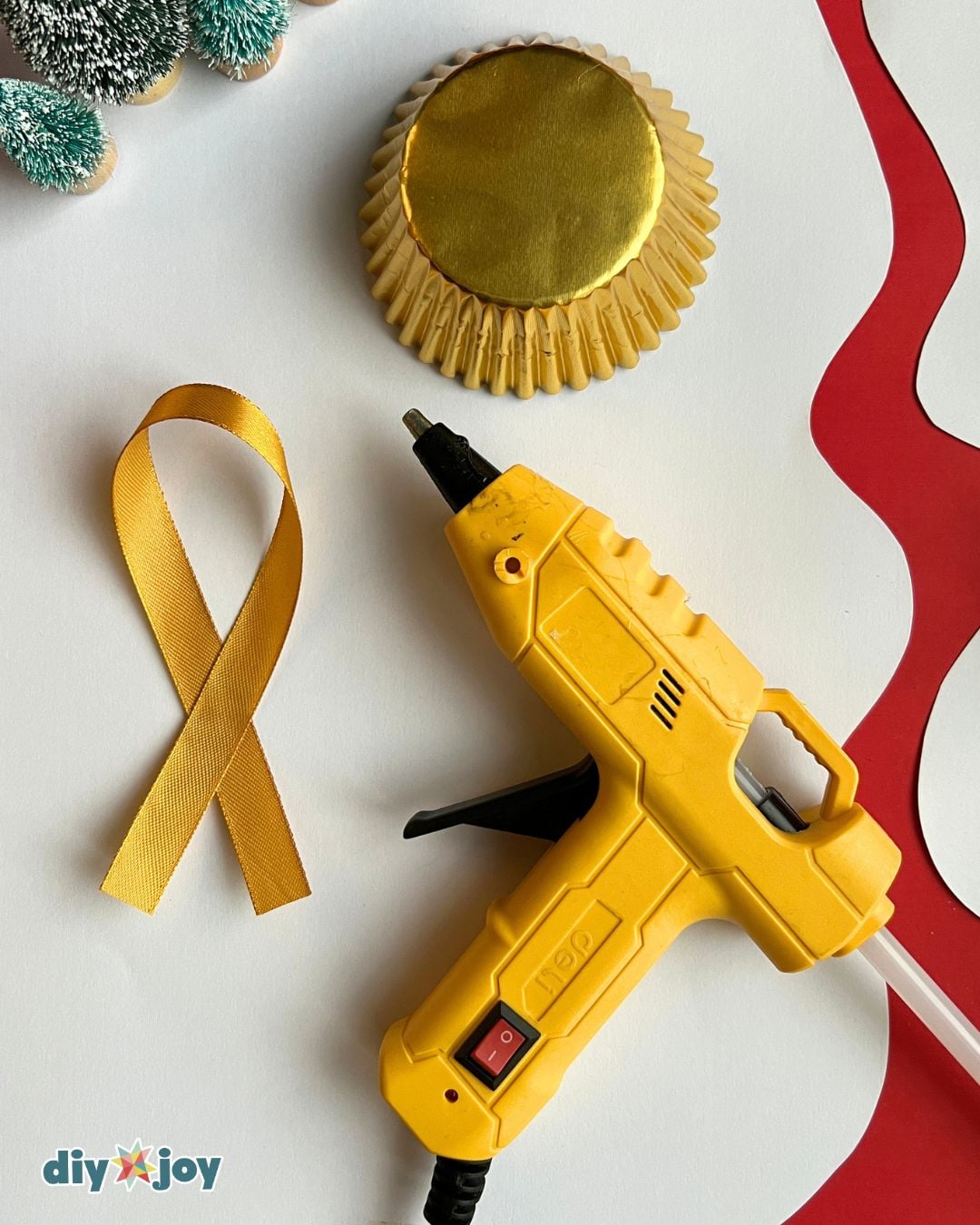 DIY Christmas Ornaments | Simple Supplies DIY Christmas ornaments supply flat lay with gold cupcake liners, ribbon and a hot glue gun on a white table