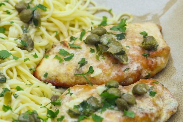 Easy Chicken Piccata Recipe, golden pan fried chicken cutlets served over angel hair pasta with capers, lemon butter sauce and parsley