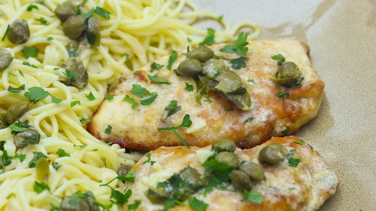Easy Chicken Piccata Recipe, golden pan fried chicken cutlets served over angel hair pasta with capers, lemon butter sauce and parsley