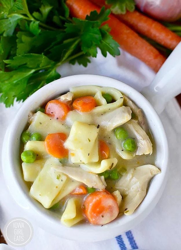 Gluten Free Homestyle Chicken And Noodles Gluten free chicken and noodles in a white bowl with wide egg noodles, carrots and peas in a creamy broth