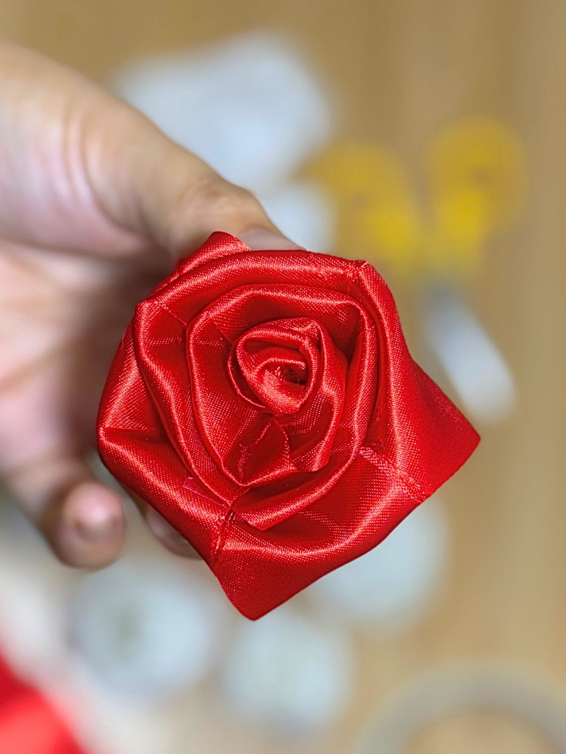 Two Minute Ribbon Rose Gift Topper A small rose rolled from a length of ribbon sitting on top of a wrapped gift as a quick elegant topper