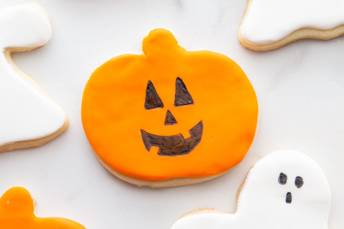 Easy Halloween Cookies for Kids Pumpkin and ghost sugar cookies topped with orange and white fondant shapes and simple edible-marker faces