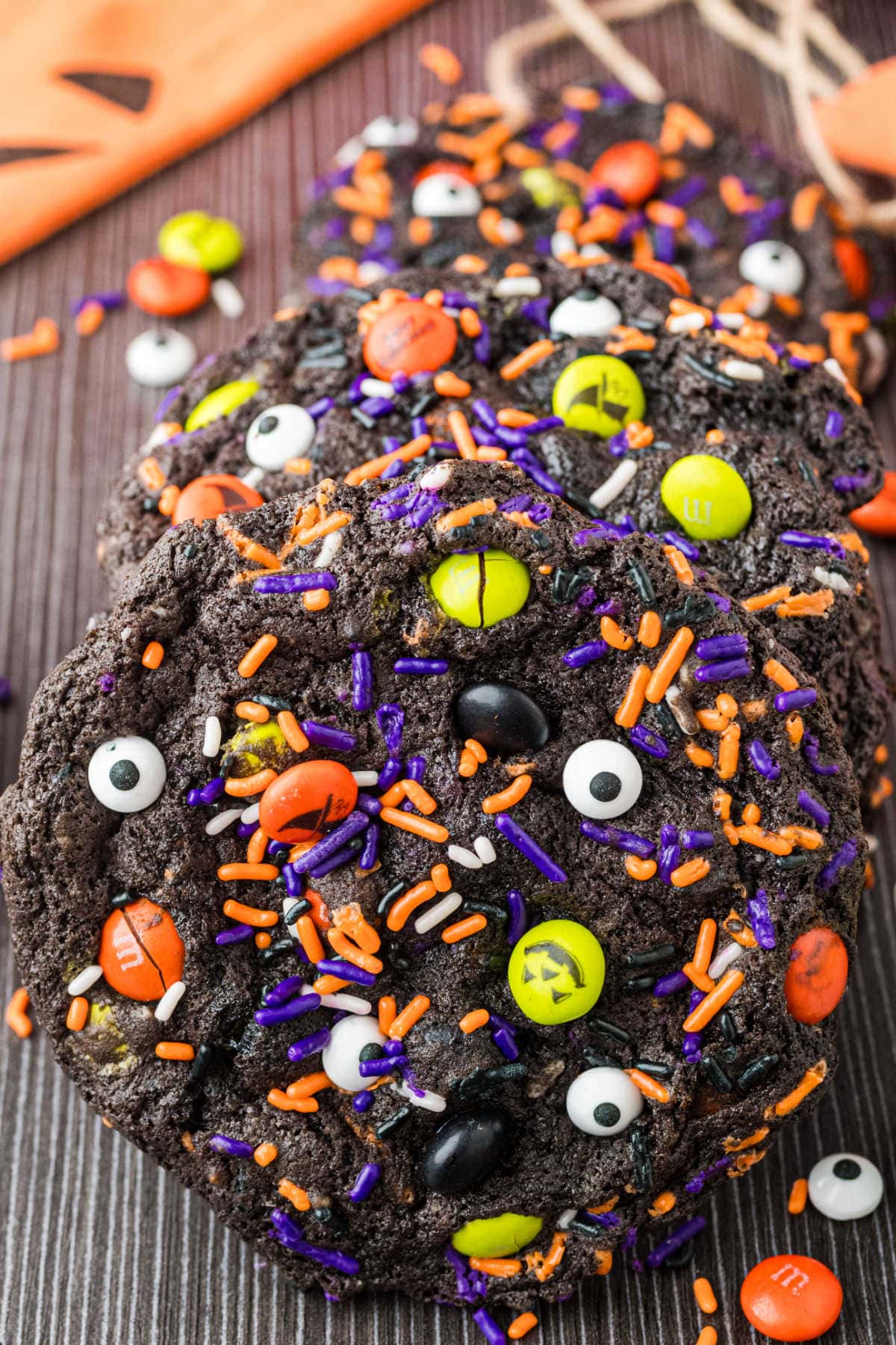 Chocolate Candy Eye Halloween Cookies Chocolate Halloween cookies with candy eyes plus orange, purple and green candy pieces on a dark serving tray