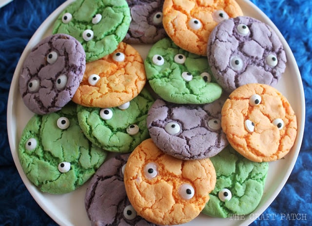 Easy Colorful Halloween Monster Cookies Orange, green and purple crackle monster cookies topped with different sizes of candy eyes on a serving plate