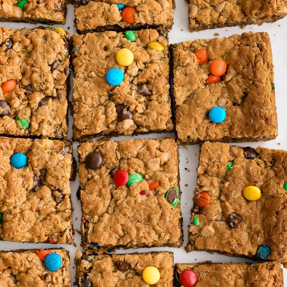 One-Pan Halloween Monster Cookie Bars Thick peanut butter oat monster cookie bars cut into squares with candy pieces and chocolate chips for Halloween