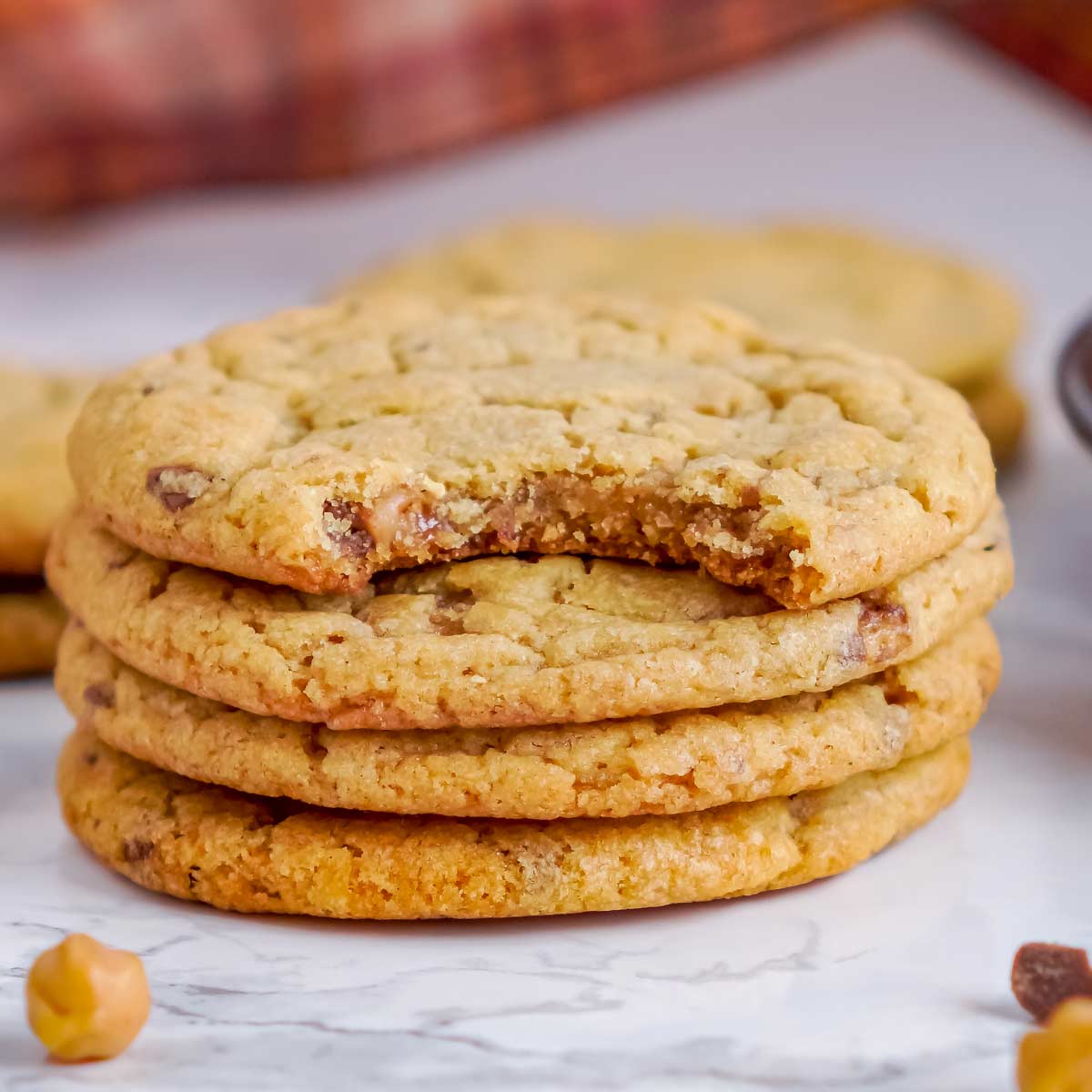 Toffee Crunch Pumpkin Cookie Recipe Stack of pumpkin cookies studded with toffee and caramel with one bitten cookie showing the soft center