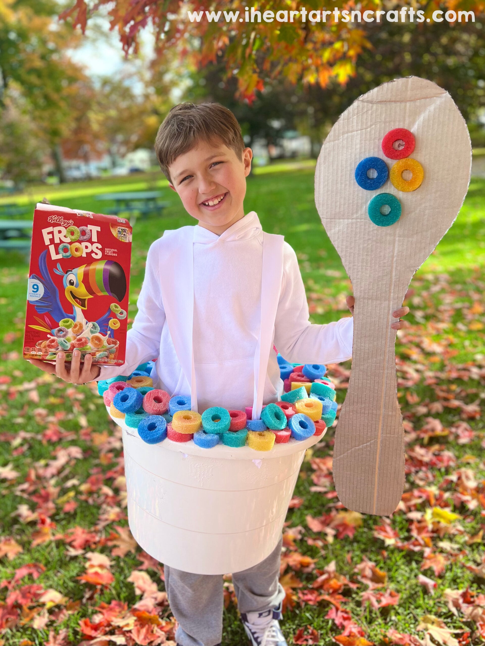 DIY Cereal Bowl Halloween Costume Child wearing a white cereal bowl costume with colorful pool-noodle cereal, cereal box and cardboard spoon outdoors