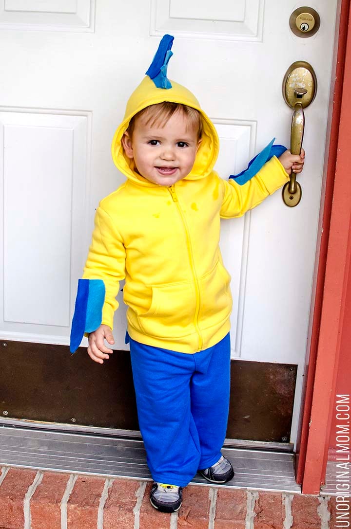 DIY No-Sew Flounder Halloween Costume Child wearing a yellow hoodie Flounder costume with blue felt fins and stripes, blue pants and source watermark