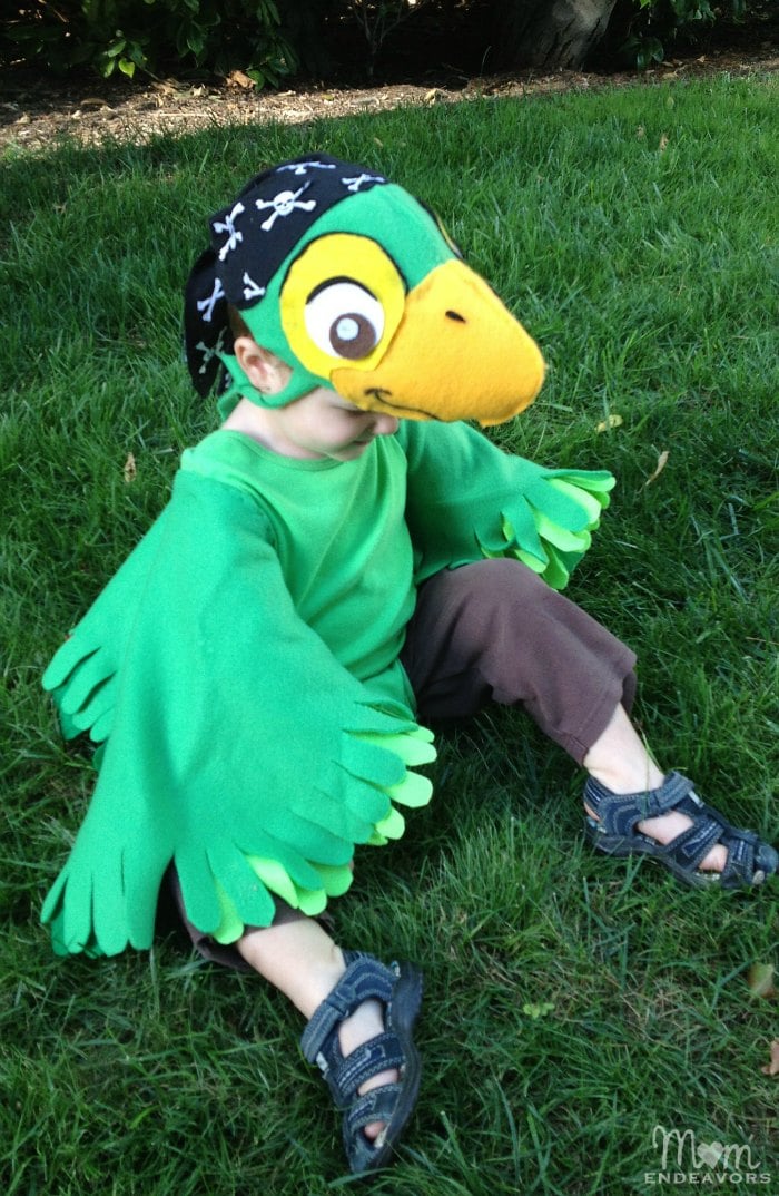 DIY Skully Parrot Halloween Costume Child wearing a Skully parrot costume with green fleece wings, layered felt feathers, a bright tail and matching cap