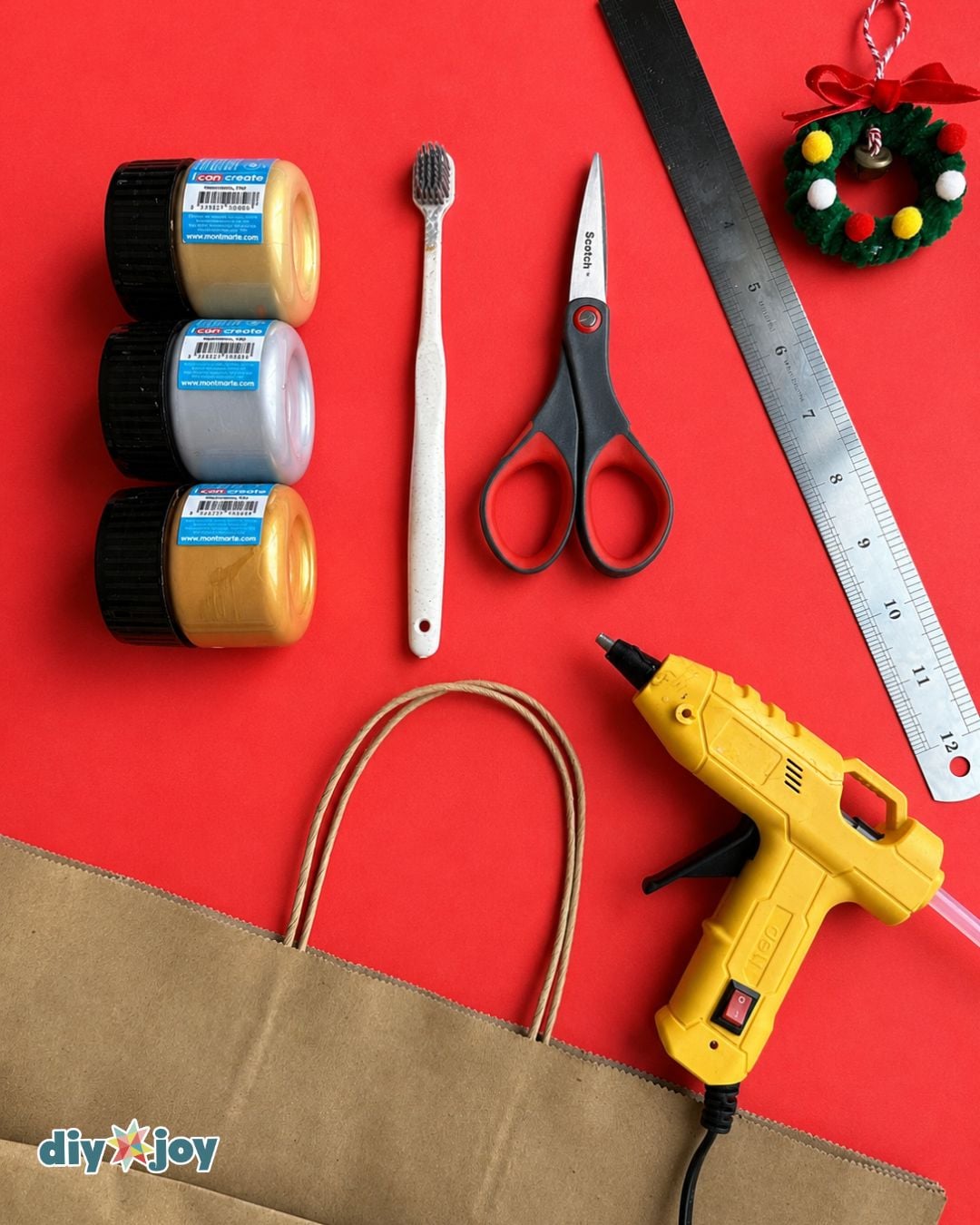 Paper star ornament supplies - paint, toothbrush, scissors, ruler, glue gun, and a paper bag for this DIY Christmas craft