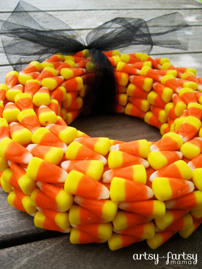Candy corn wreath with alternating orange, yellow and white rows, a black tulle bow and Artsy-Fartsy Mama watermark