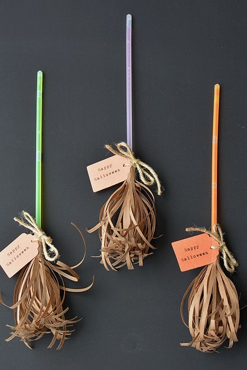 Glowing bracelet sticks dressed as miniature witch broomsticks with kraft paper bristles and tied twine