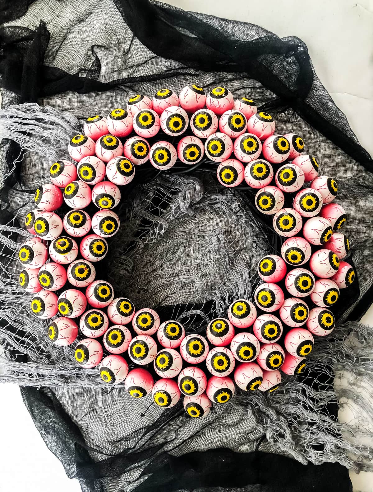Black grapevine wreath covered with many white foam eyeballs and finished with a dark ribbon for hanging