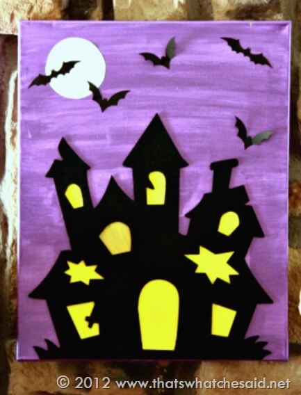 Purple canvas with black haunted house and bats, white moon, yellow windows and source watermark in view