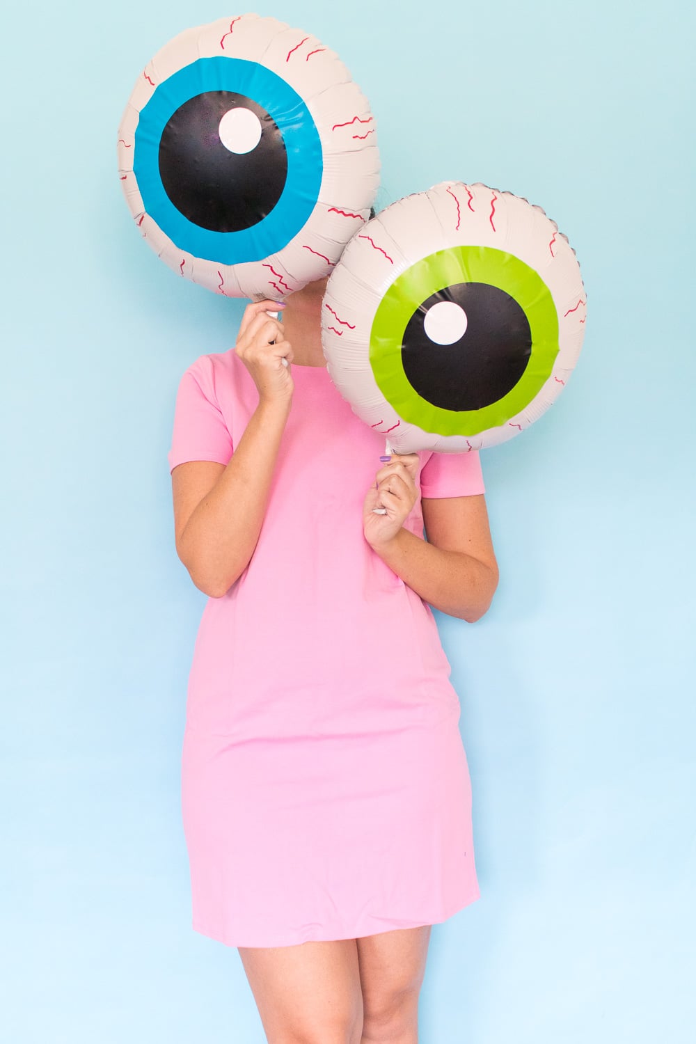 Two white mylar eyeball balloons show blue and green vinyl irises, black pupils and red marker veins