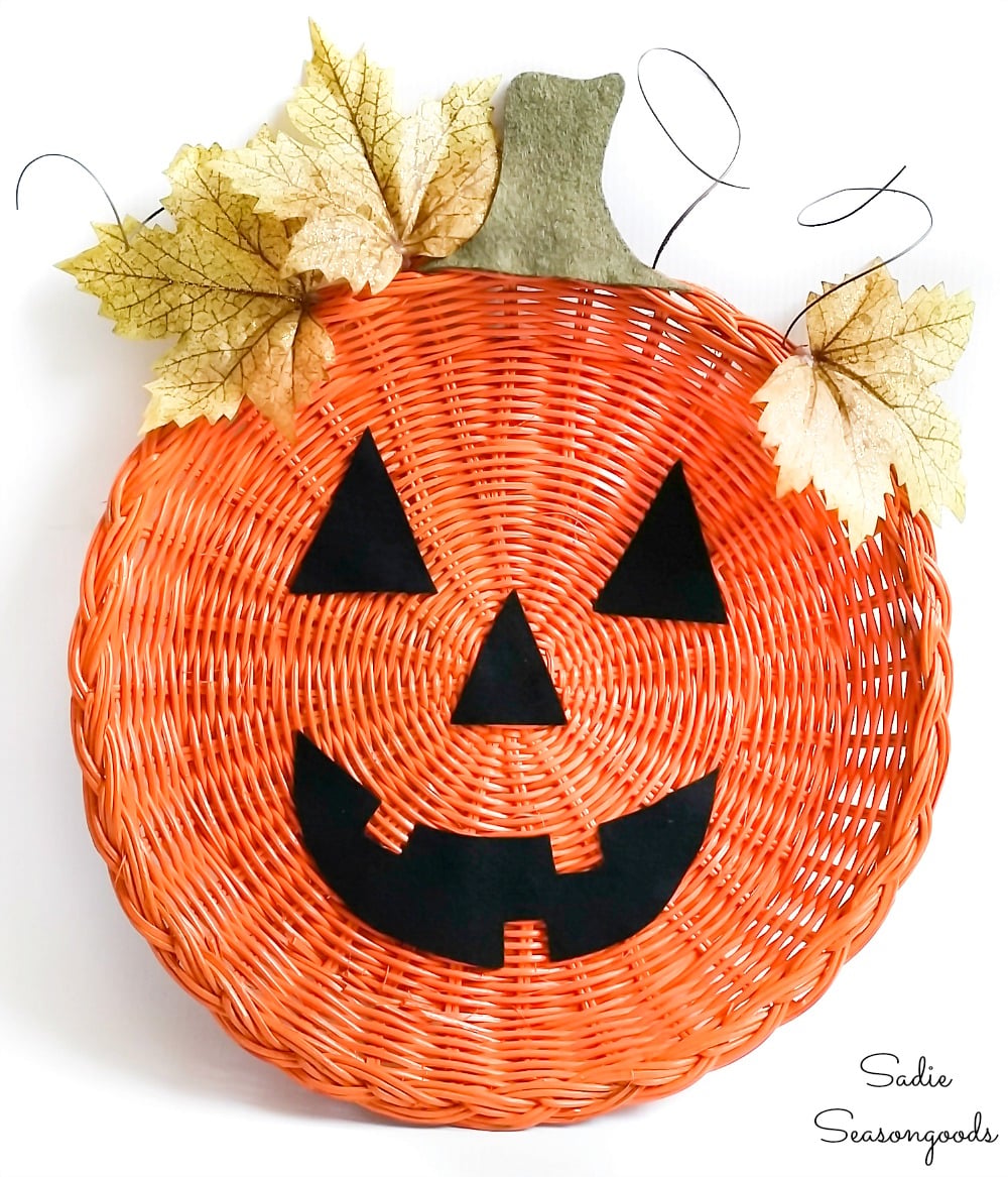 Orange wicker paper plate holder becomes a jack-o-lantern door hanger with felt face and green accents