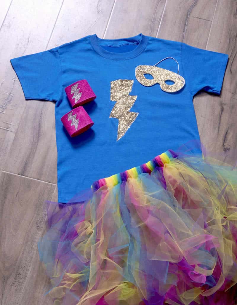 Blue superhero shirt with silver lightning bolt, pink cuffs, silver mask and rainbow tulle skirt arranged flat