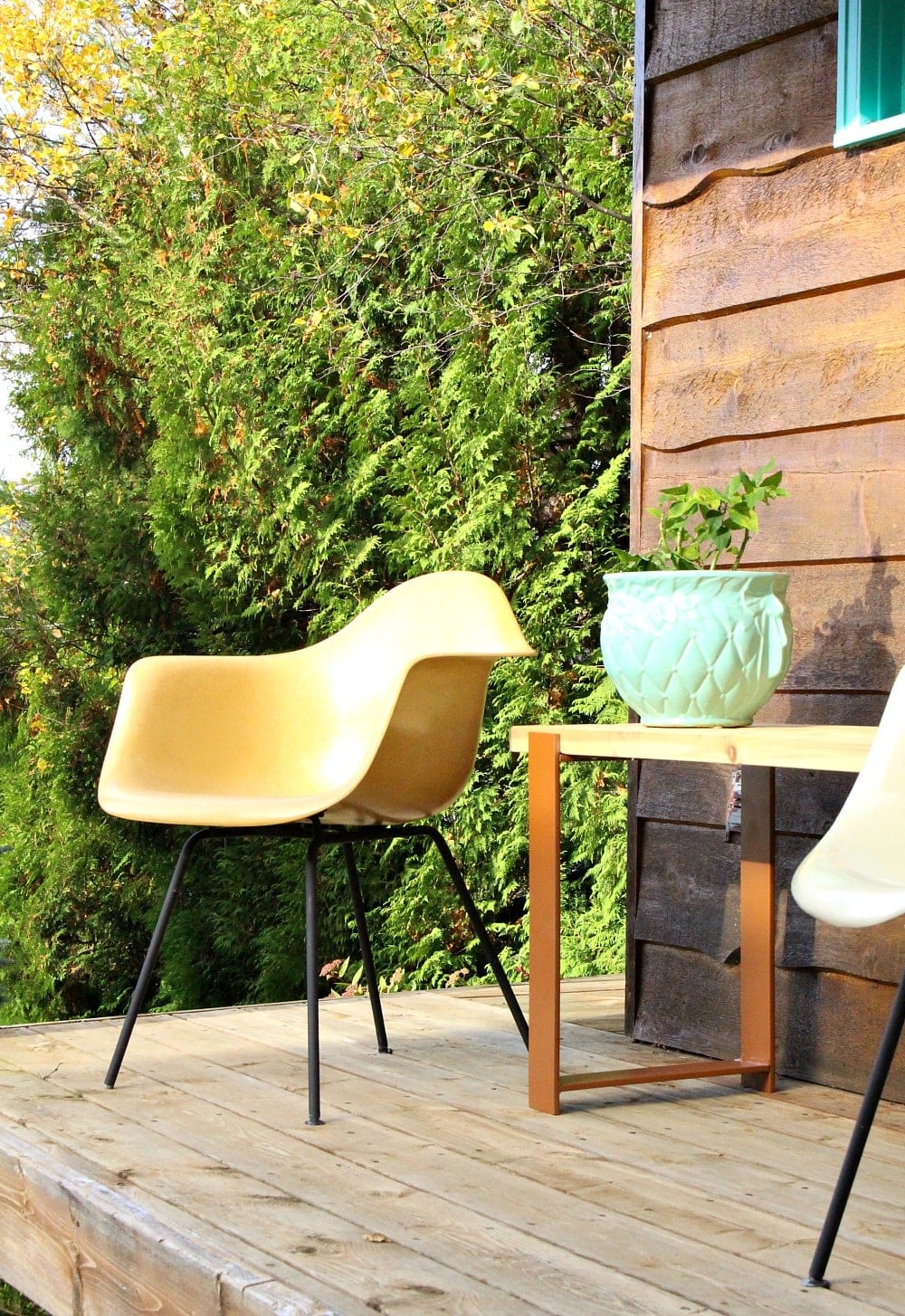2x4 Bench With Welded Legs | DIY Patio Furniture Idea Outdoor wood bench with welded steel legs on a wood deck beside a yellow molded chair and a planter of green plants