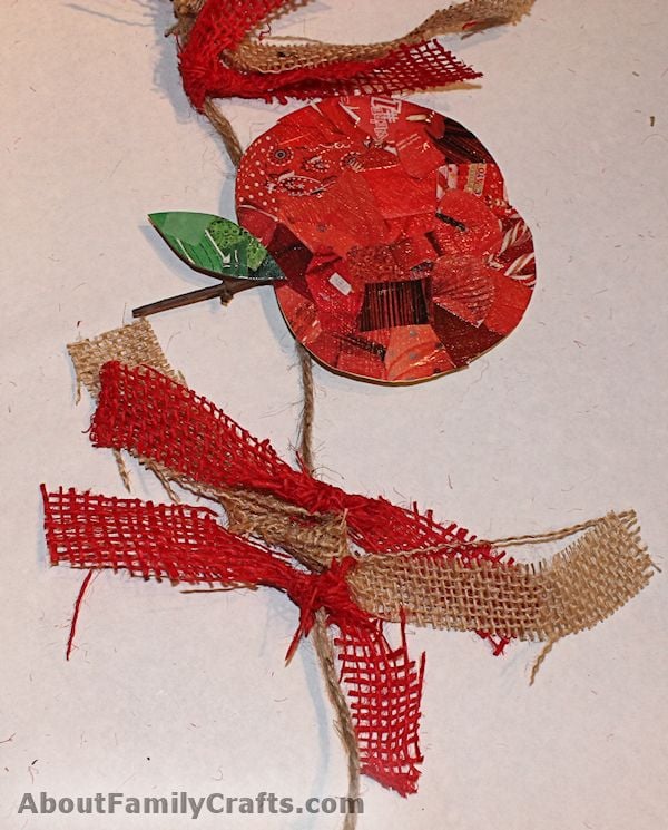 DIY recycled apple bunting with red decoupage catalog paper apples and green leaves on twine with red fabric strips