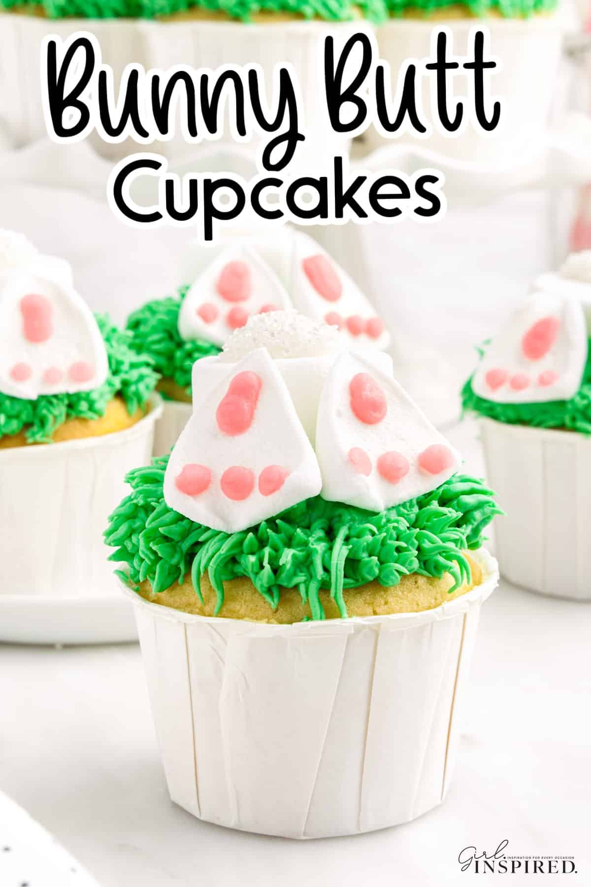 Cupcakes with green piped grass frosting topped with white bunny bottoms and pink-padded feet
