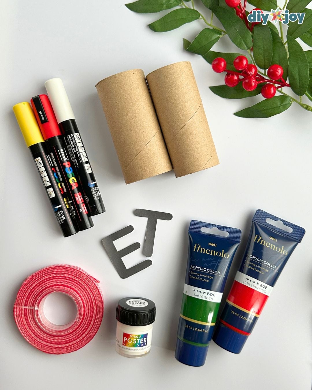 Supplies for a toilet paper roll Christmas banner: cardboard tubes, acrylic paint, paint markers, ribbon, water and a brush