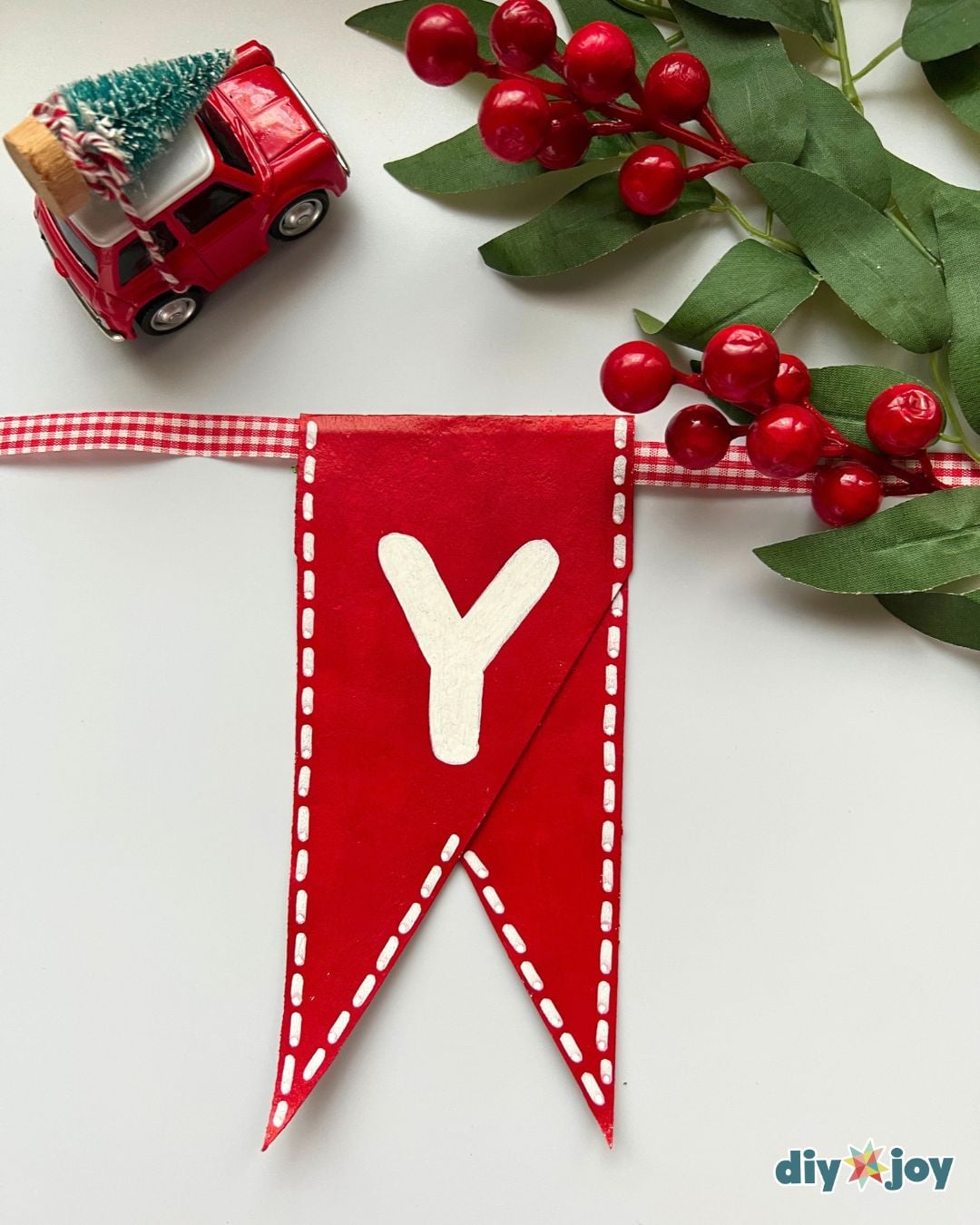 Pennants strung on ribbon and taped closed to finish a toilet paper roll Christmas banner, easy DIY Christmas decor to hang