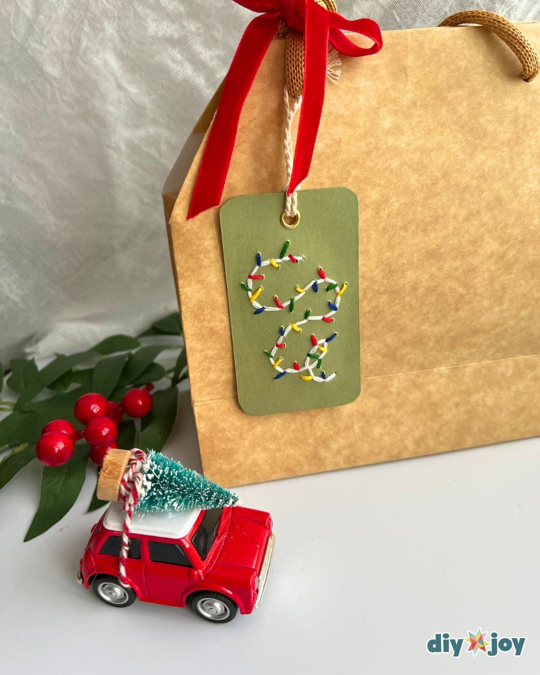 Cute gift tag idea - embroidered Christmas lights gift tag tied to a kraft paper gift bag with a big red bow