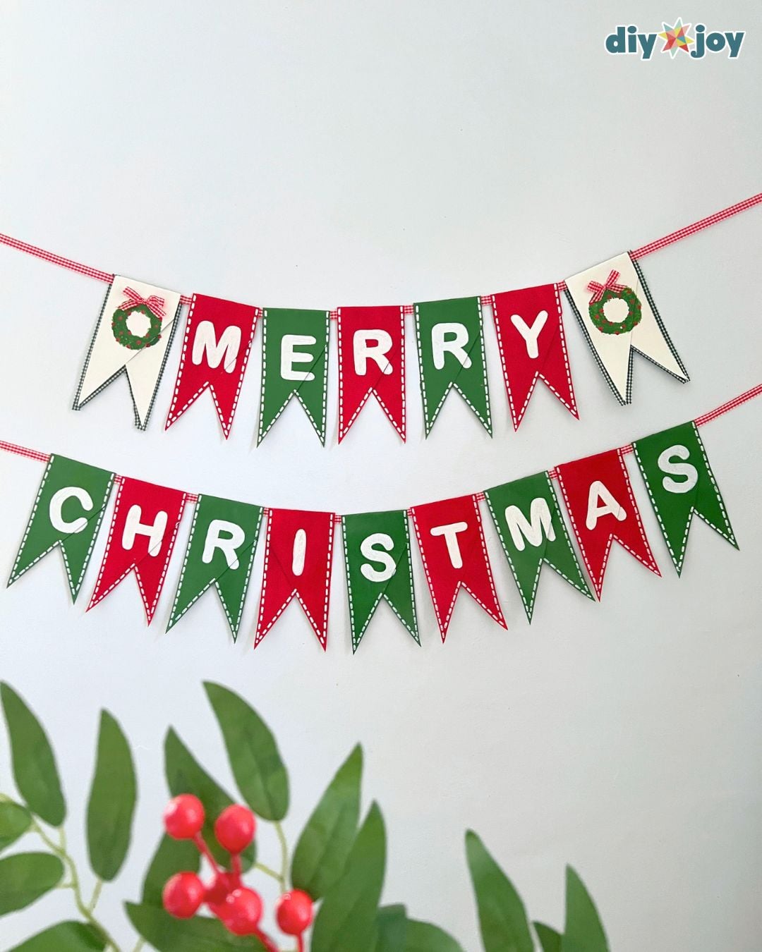 Finished toilet paper roll Christmas banner spelling Merry Christmas on red, green and white cardboard pennants on ribbon