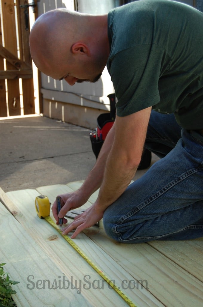 DIY fence table, a mint painted slatted table hinged up flat against a tall wooden fence on one angled brace