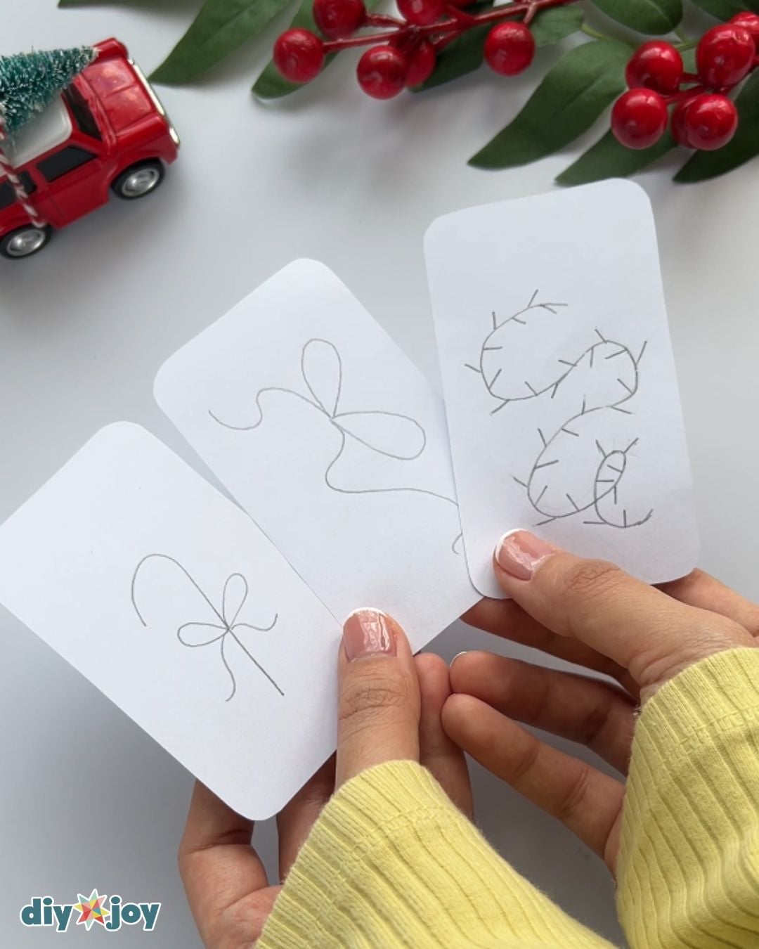 Embroidered gift tag pattern - drawing a bow and a string of lights on white paper with a pencil before stitching