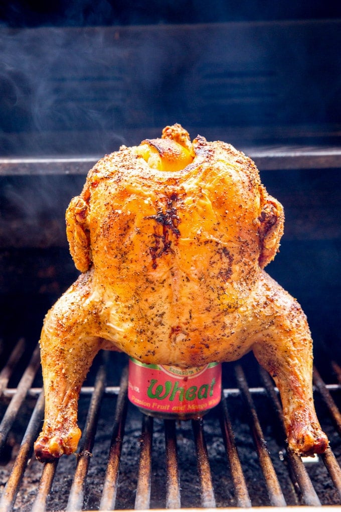 Grilled Beer Can Chicken Whole seasoned chicken roasting upright on a beer can on grill grates