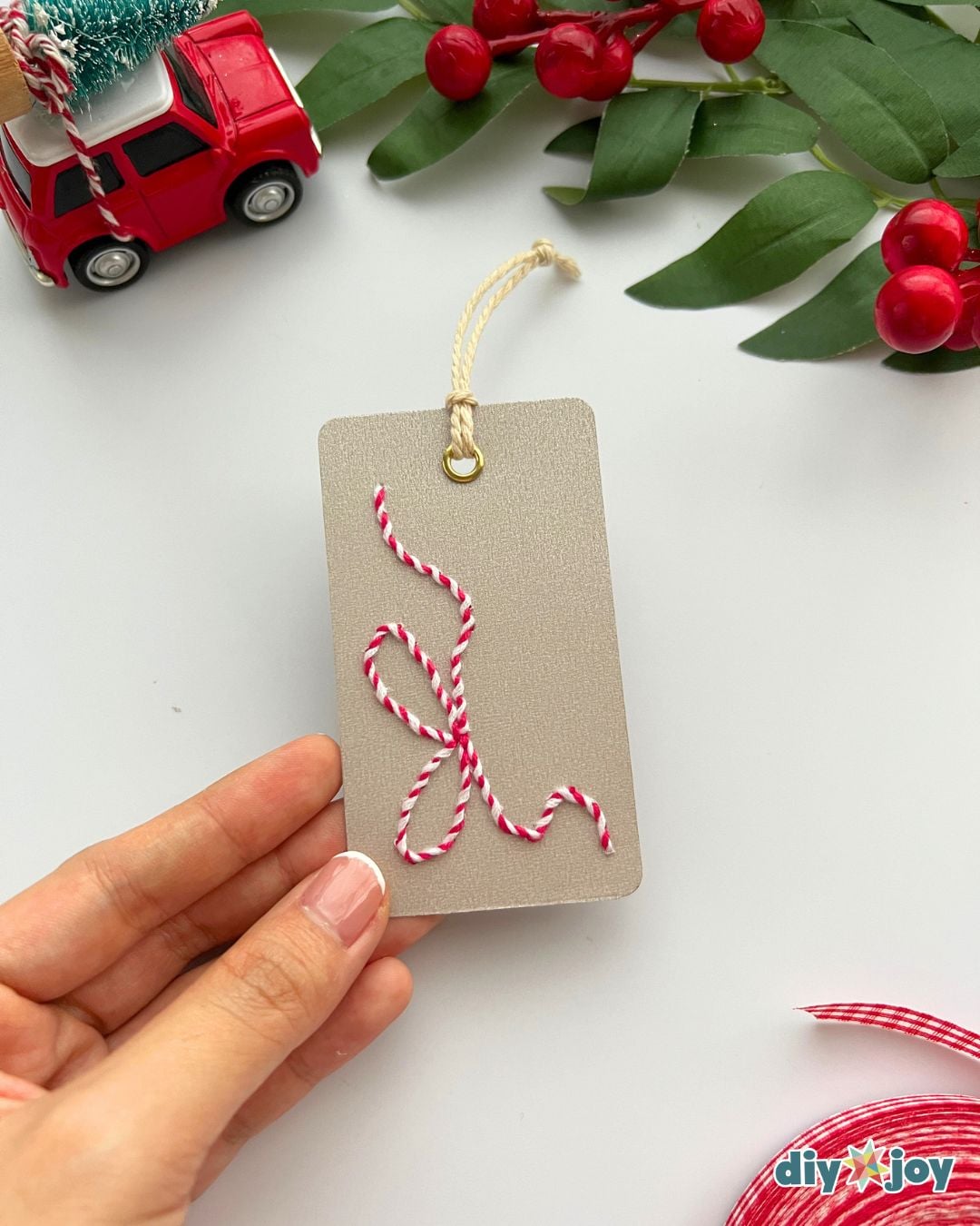 Hand stitched gift tags - kraft cardstock tag with a red and white candy cane and yellow bow held in one hand