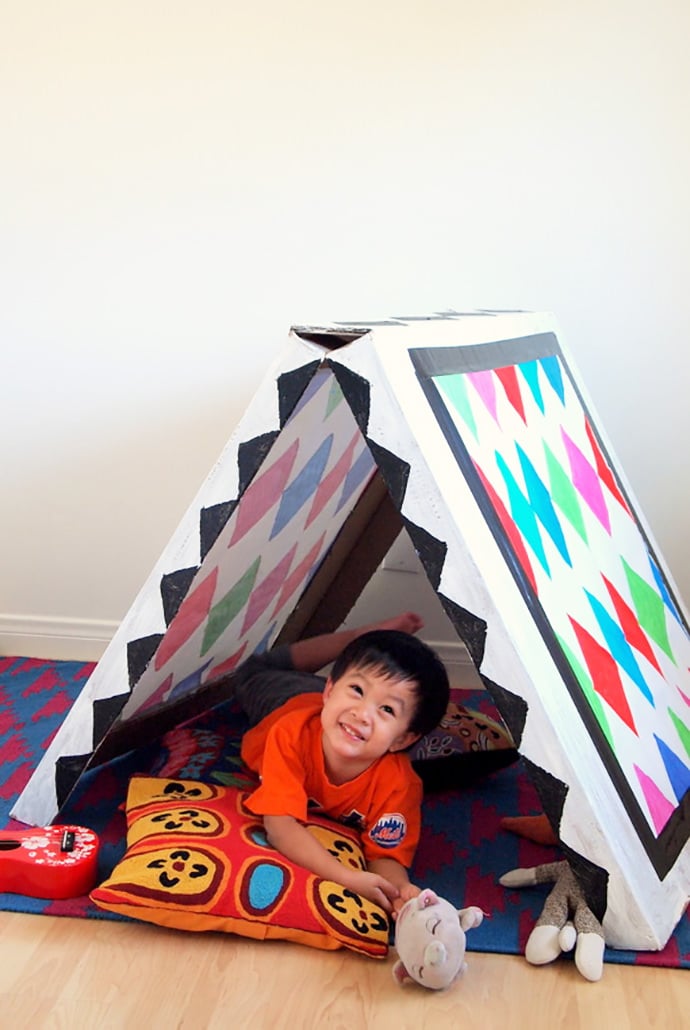 Collapsible Cardboard Play Tent That Folds Flat Cardboard craft A frame play tent painted with chevrons and diamonds on a patio rug with soft toys inside