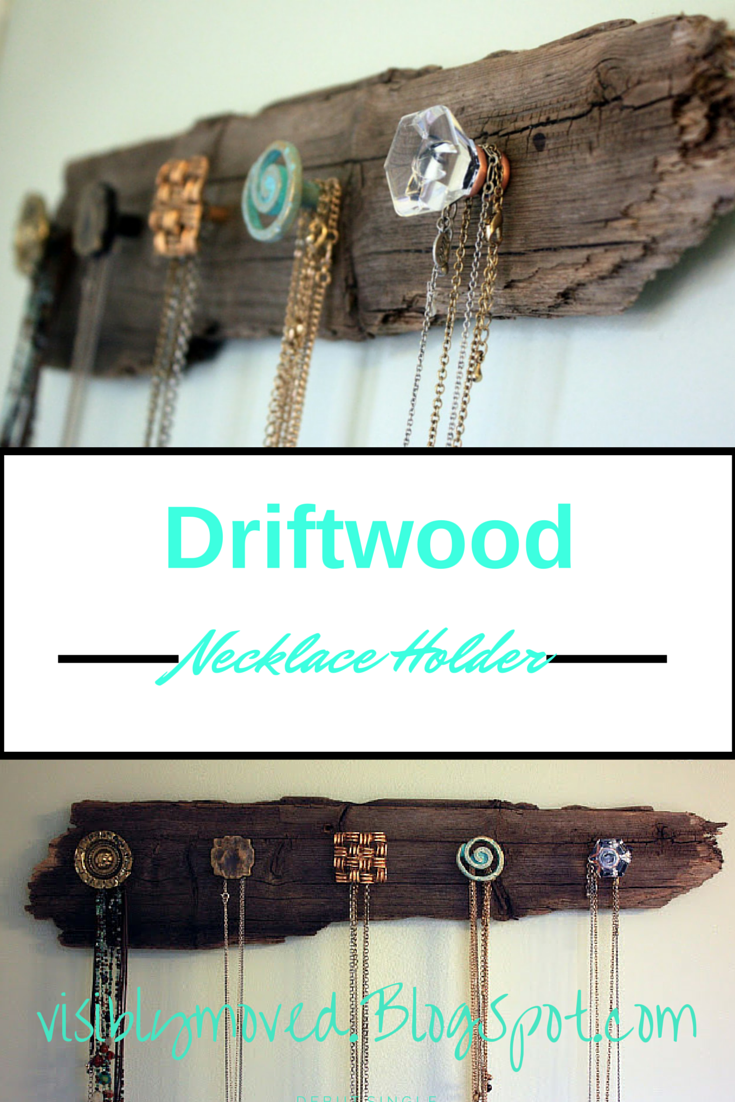 Driftwood necklace holder with glass, metal and ceramic knobs holding gold and beaded necklaces on a white wall