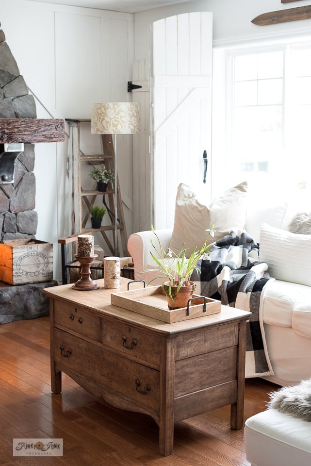 Antique wood dresser cut down into a low coffee table with drawers, a wooden tray and a plant in a cozy white living room
