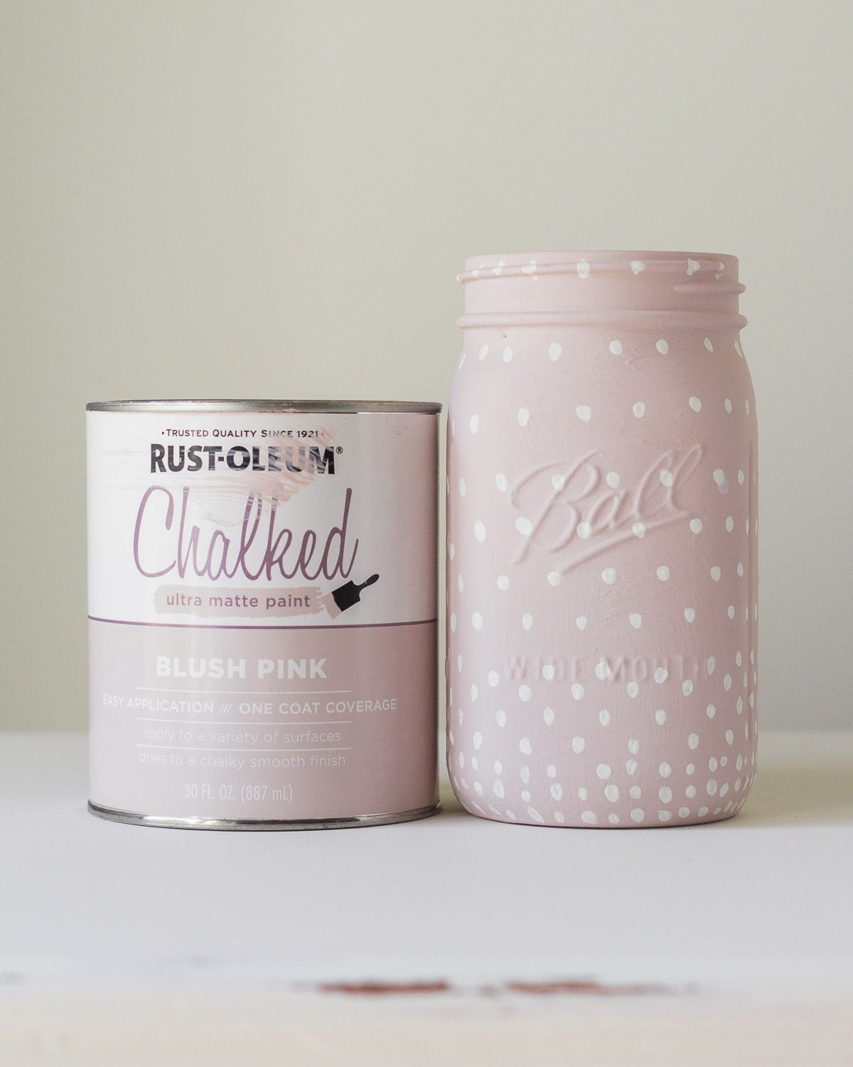 Blush pink chalk painted mason jar vase covered in creamy white dots that spread farther apart toward the rim